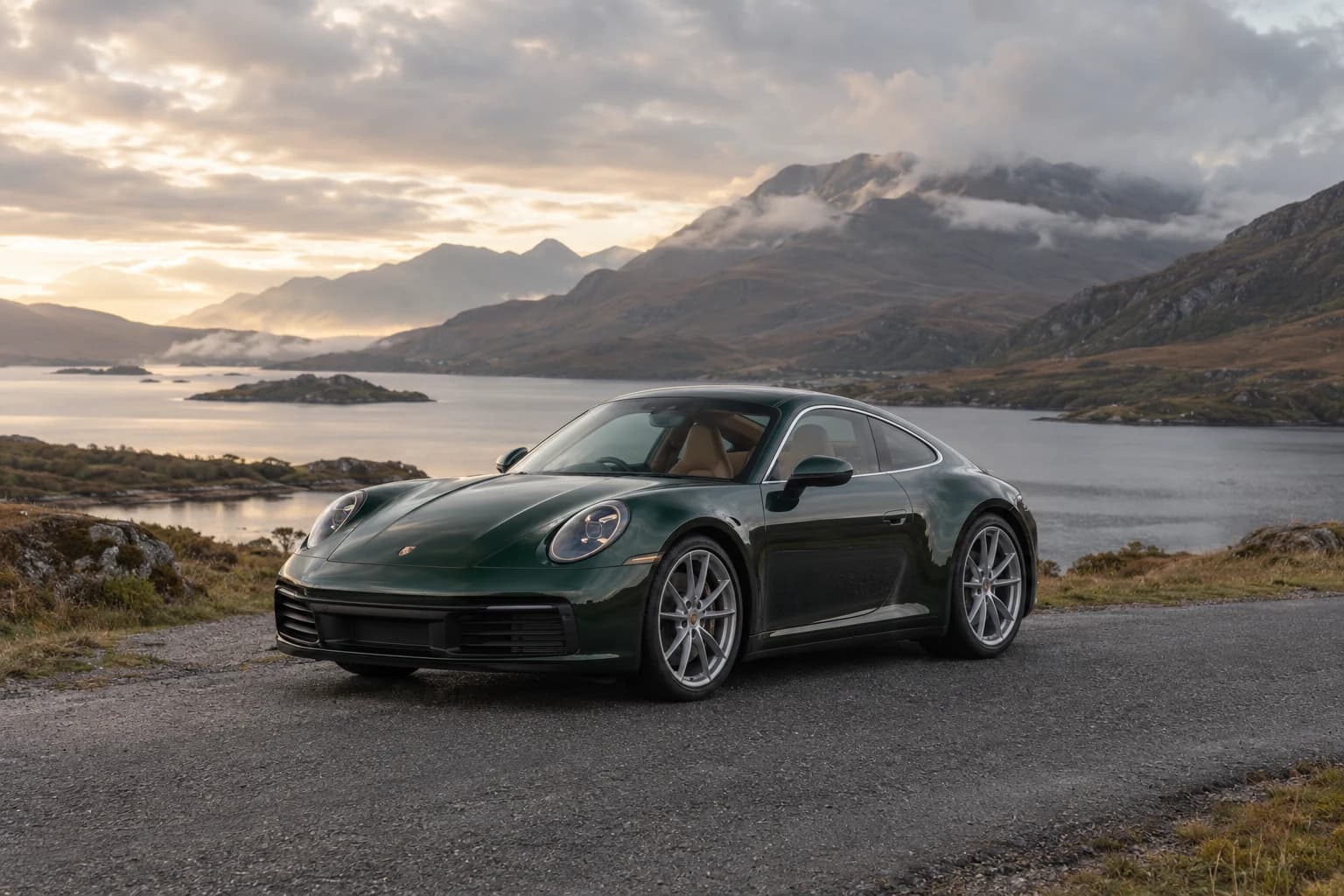 A forest-green Porsche 911 on a quiet Highland road